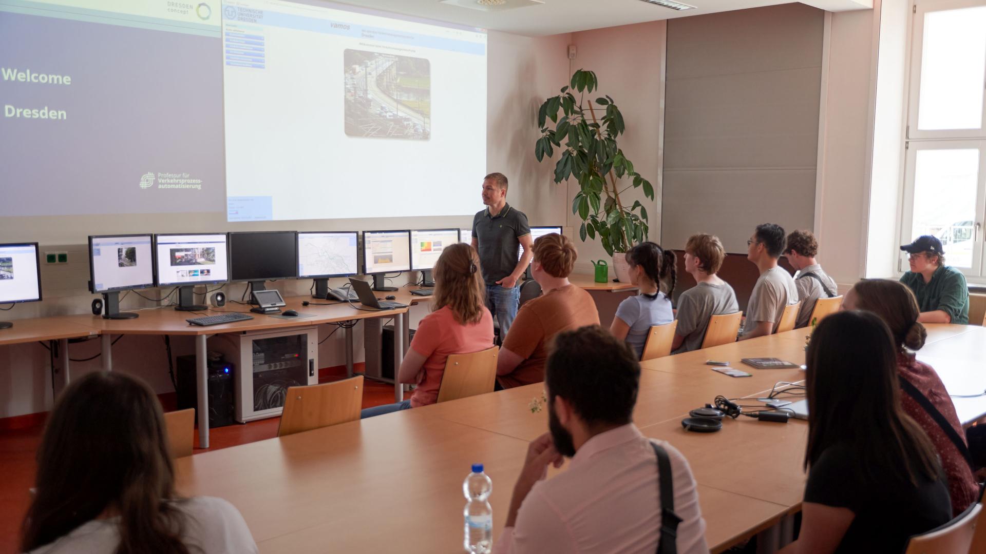 Studierende sitzen in einem Raum und schauen auf eine Präsentation