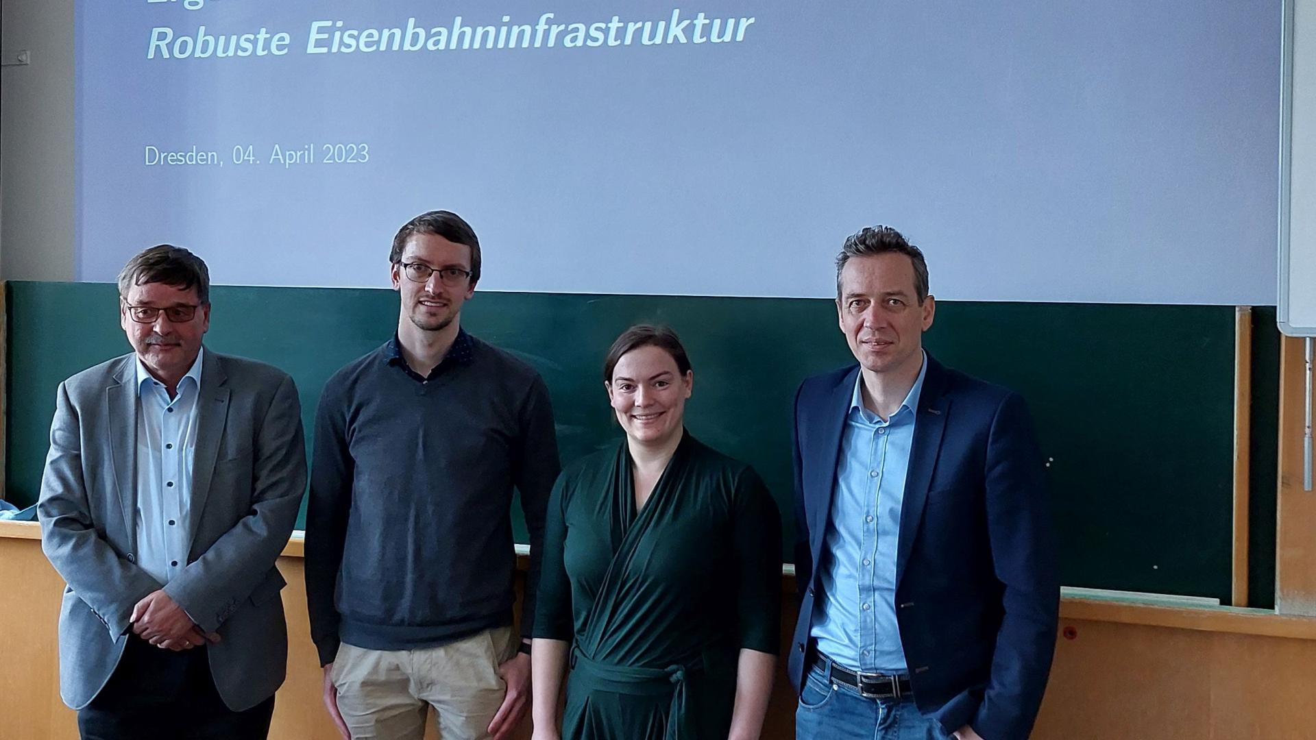 Eine Gruppe von 5 Menschen steht vor einer Tafel