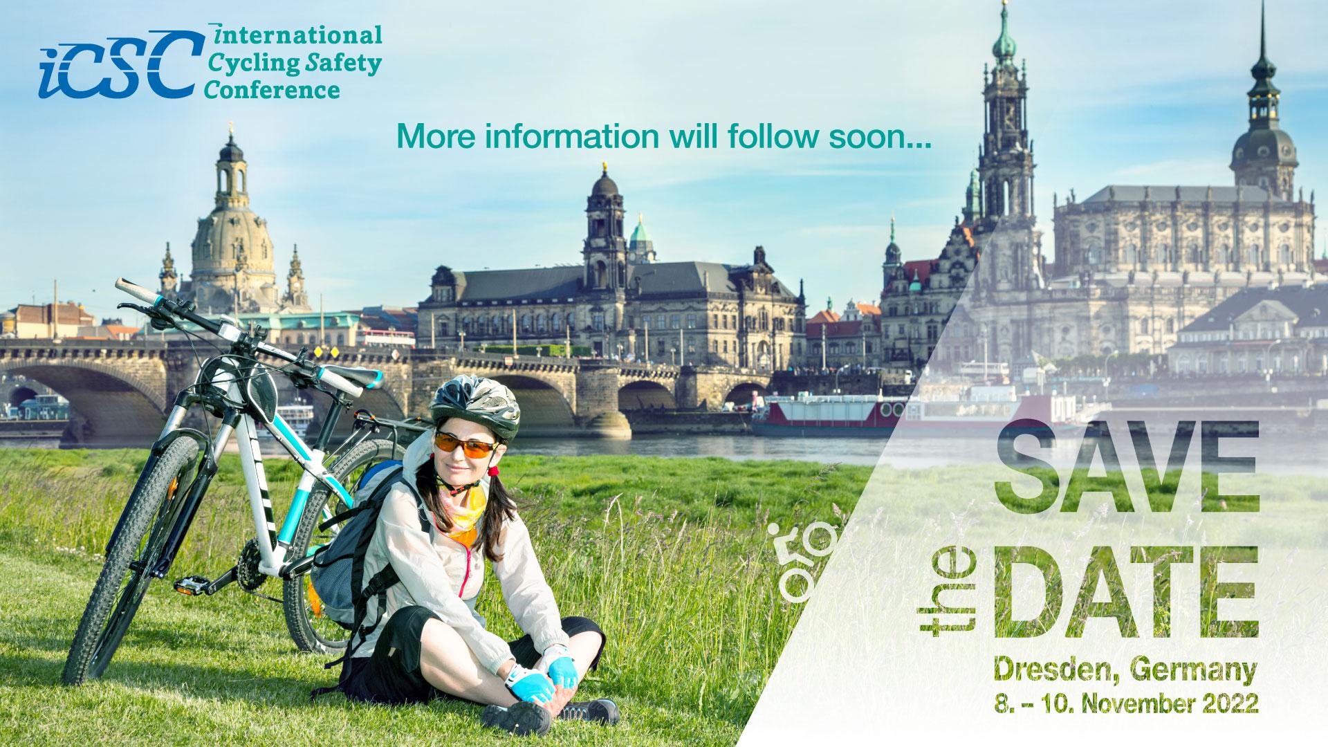 A cyclist sits on a meadow, her bike next to her, the old town of Dresden in the background.