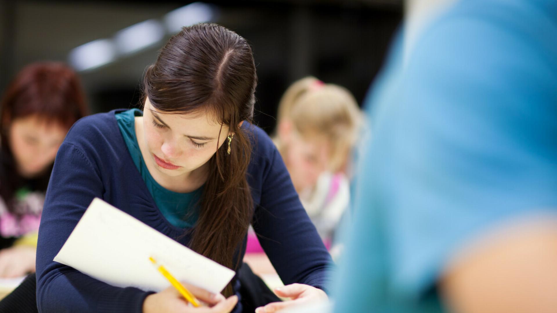 The photo shows concentrated students writing an exam.