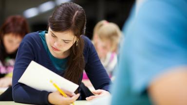 The photo shows concentrated students writing an exam.