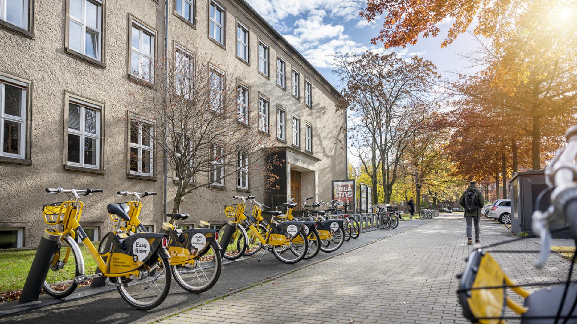 Exterior view of a TUD building with yellow rental bikes in front of it.