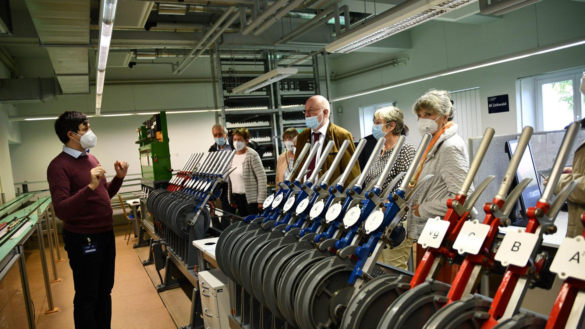 Personen in einem Eisenbahnlabor. Im Vordergrund Stellhebel.