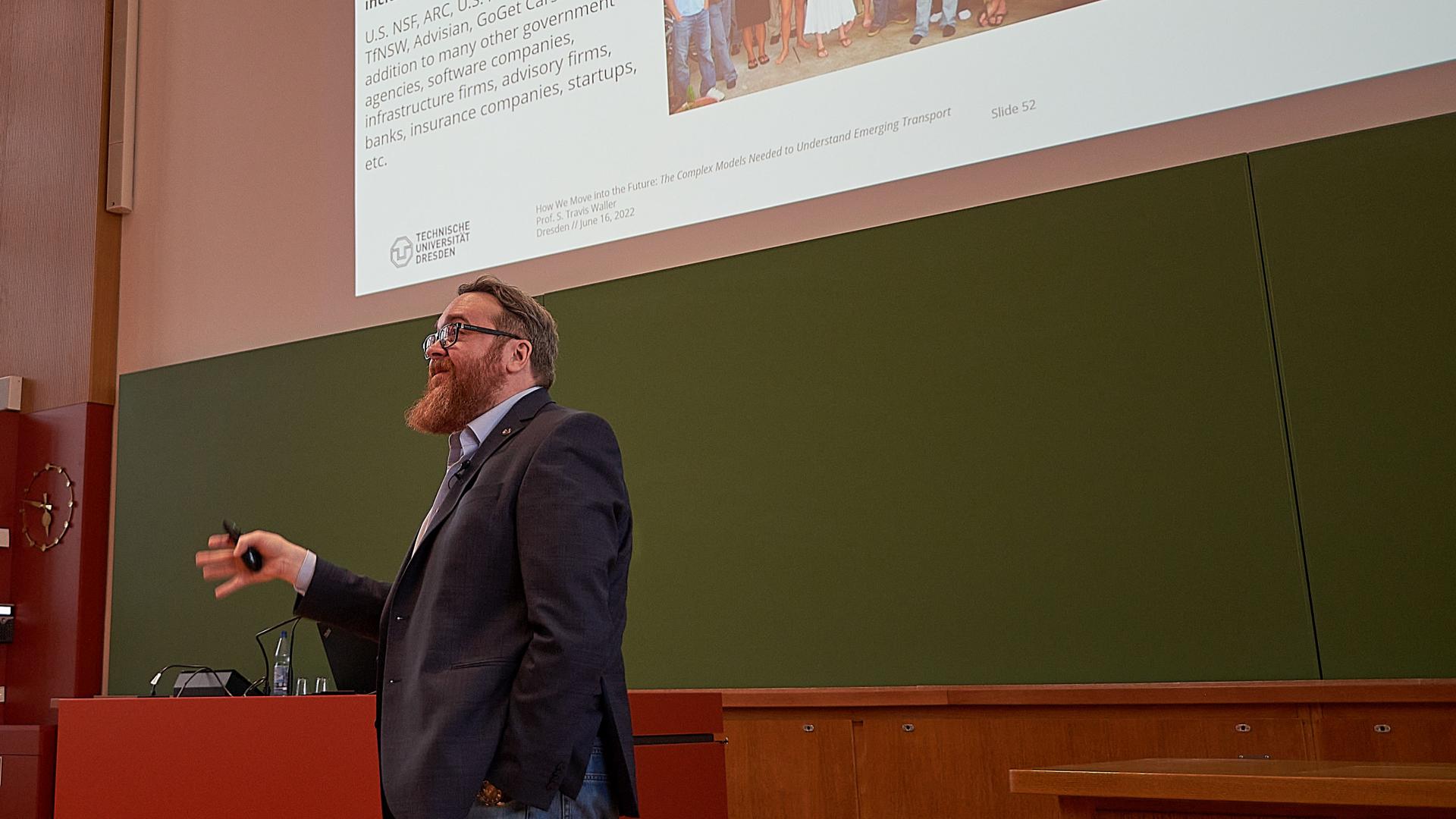 A man gives a lecture in a lecture hall in front of a blackboard