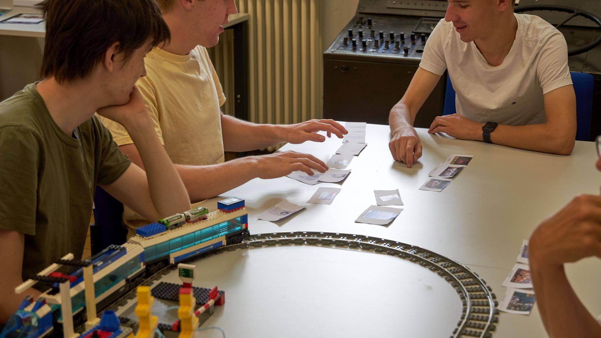 Three students sort cards on a table