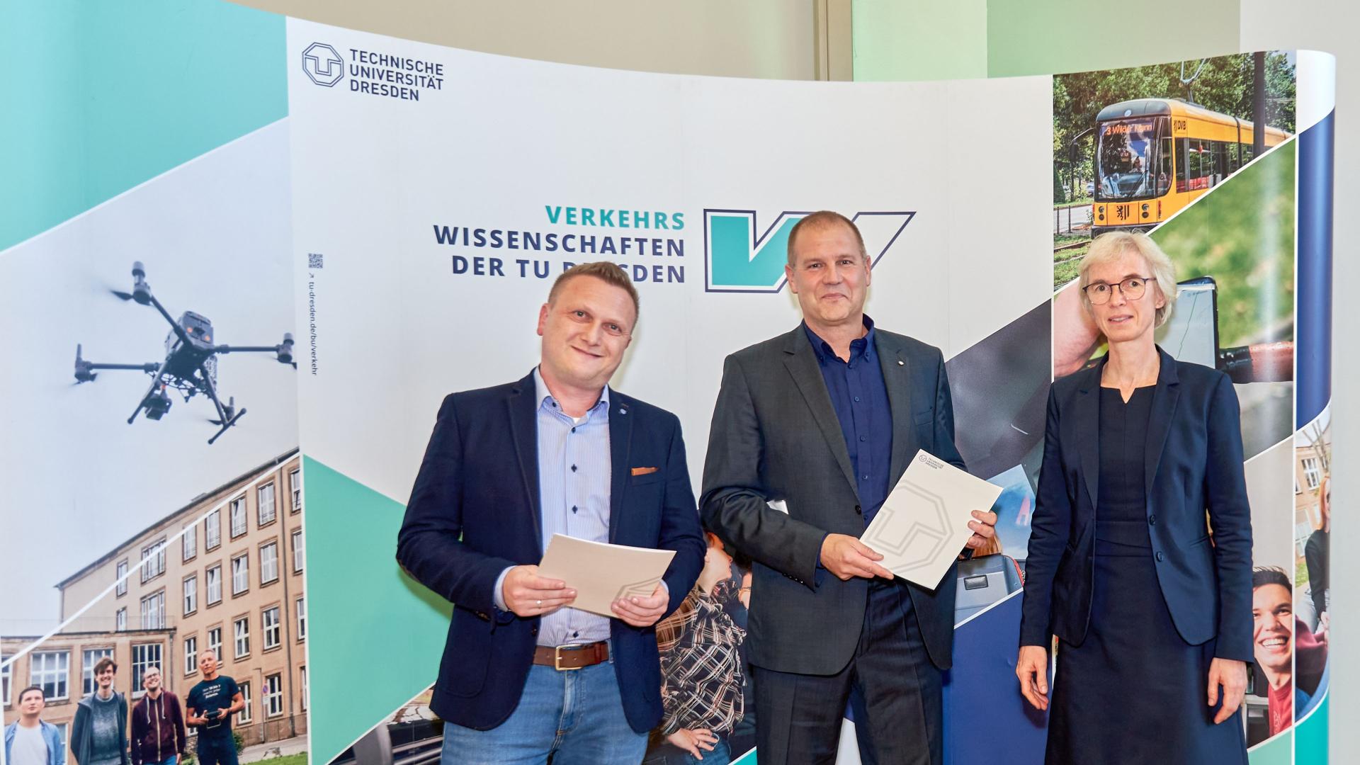 3 Menschen vor einer Fotowand