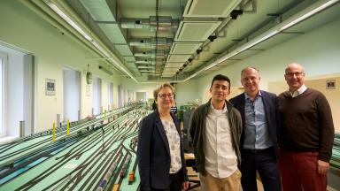 A woman, a student and two men stand in the railway operation laboratory at TU Dresden