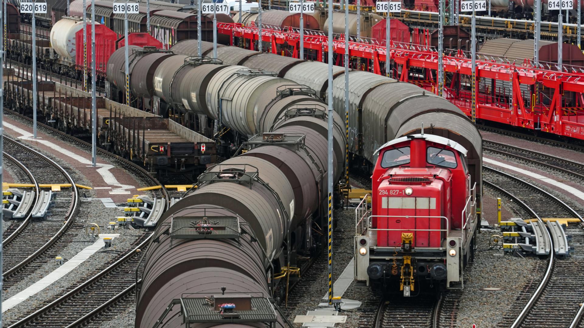 A marshalling yard with many trains with wagons. A locomotive is pulling a train.