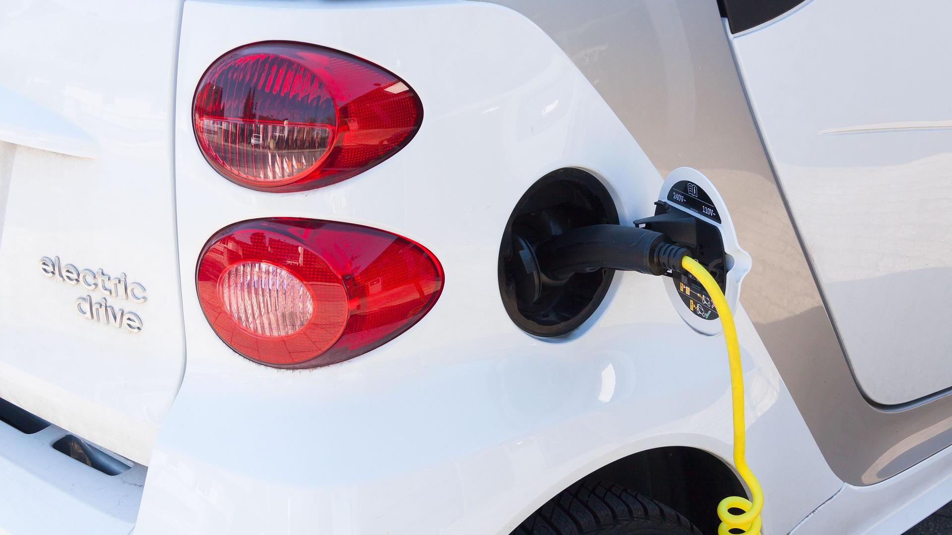 A small electric car refuelling at a charging station
