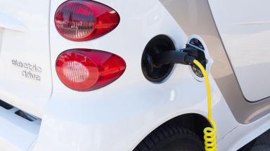 A small electric car refuelling at a charging station