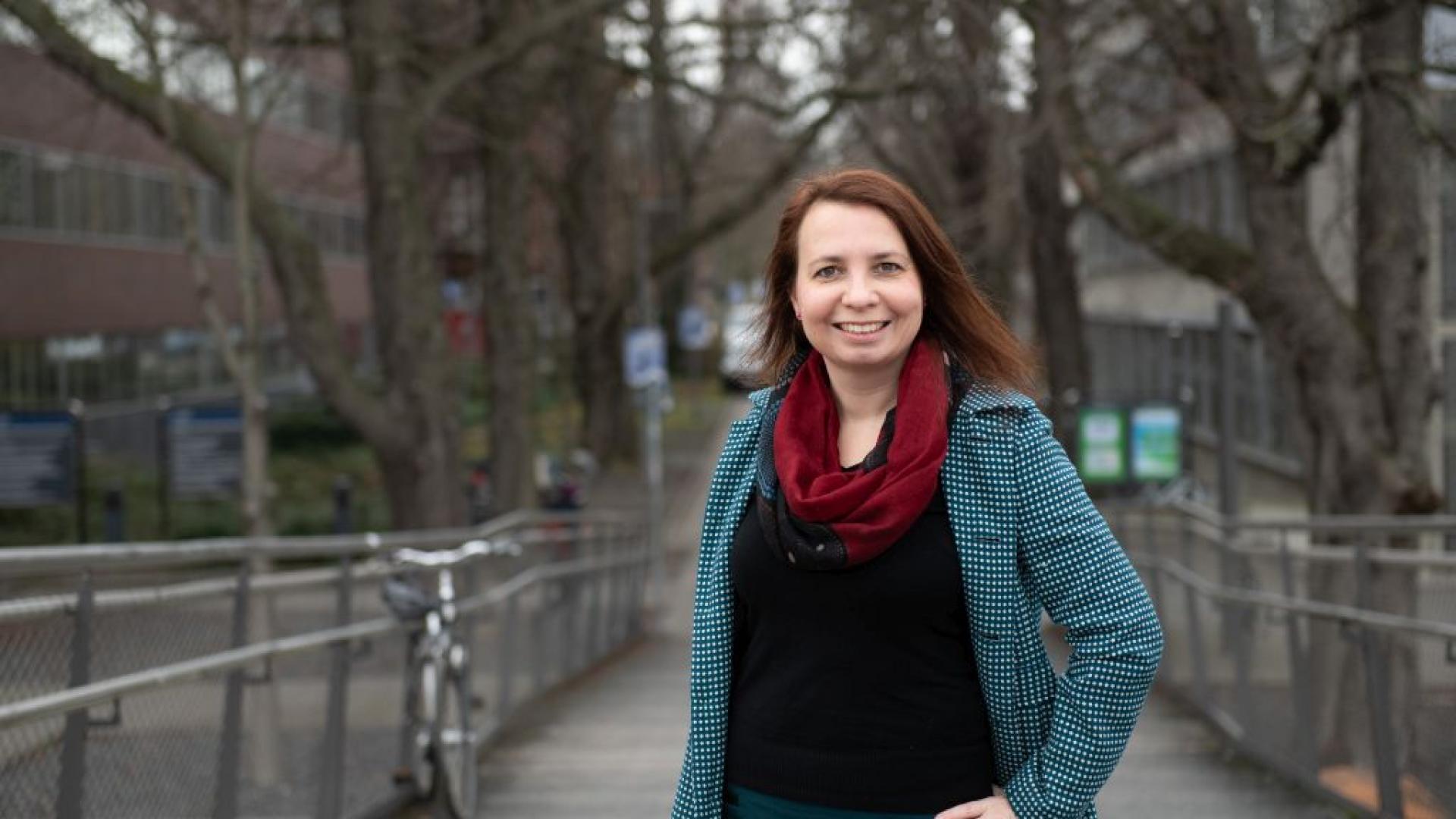 Porträtfoto von Angela Francke im Mantel und mit Hand in die Seite gestützt.