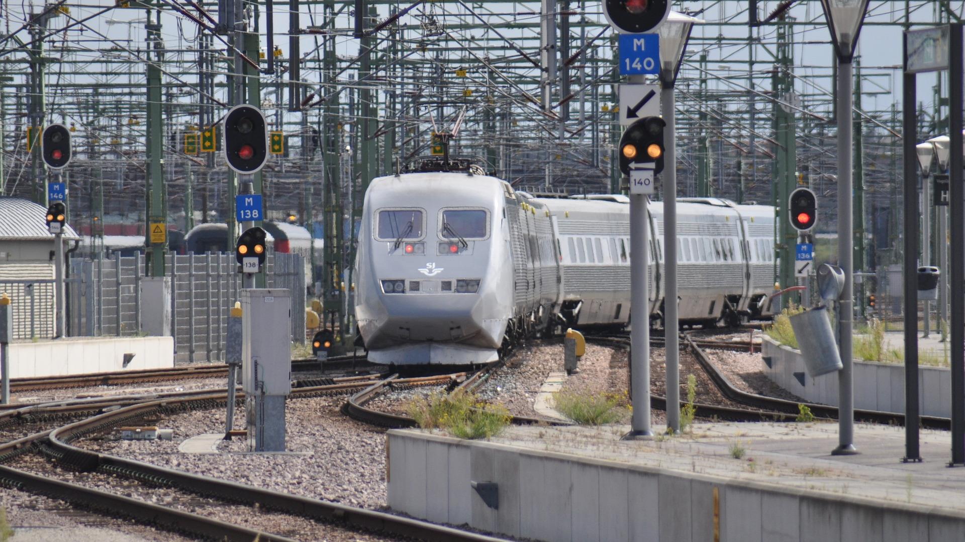 Ein grauer Zug zwischen vielen Gleisen und Oberleitungen
