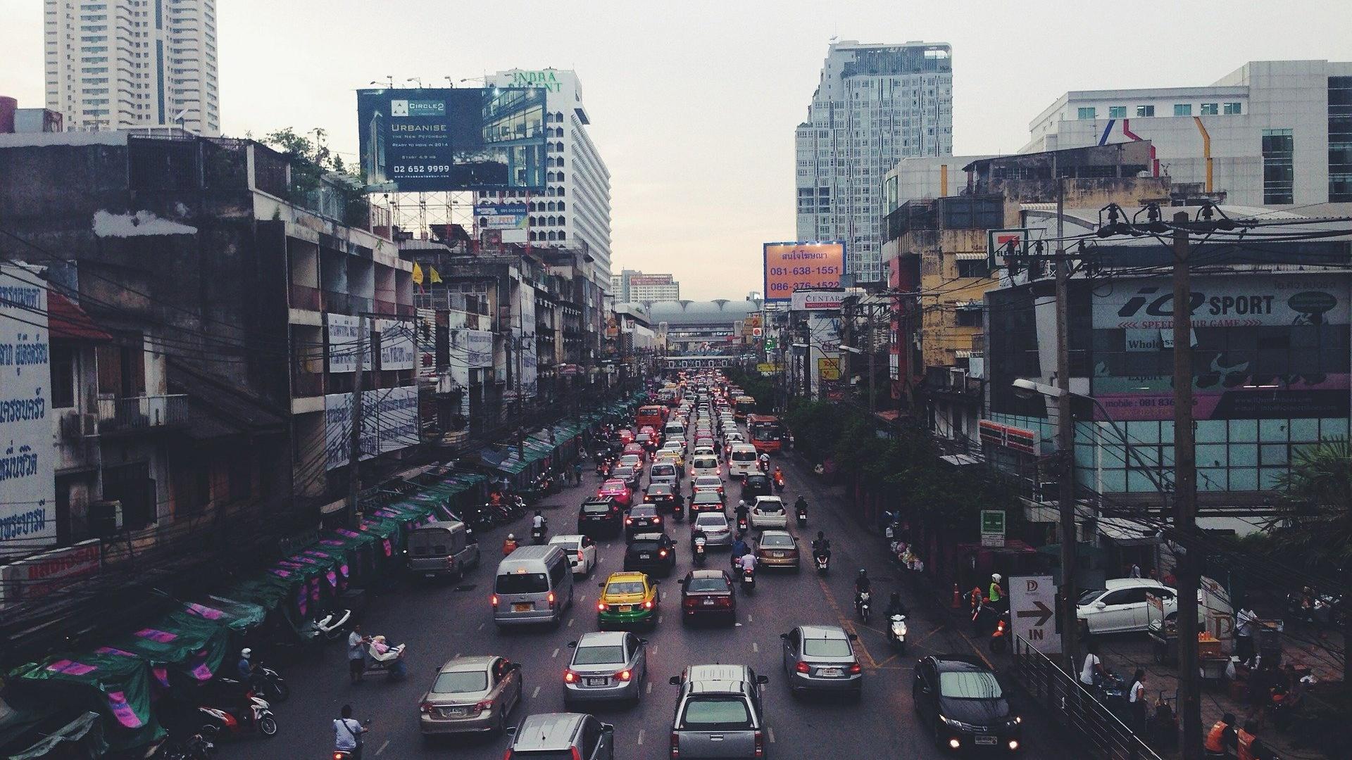 Häuserschluchten einer Großstadt in Indien mit Verkehrsstau, Autos, Mofas.