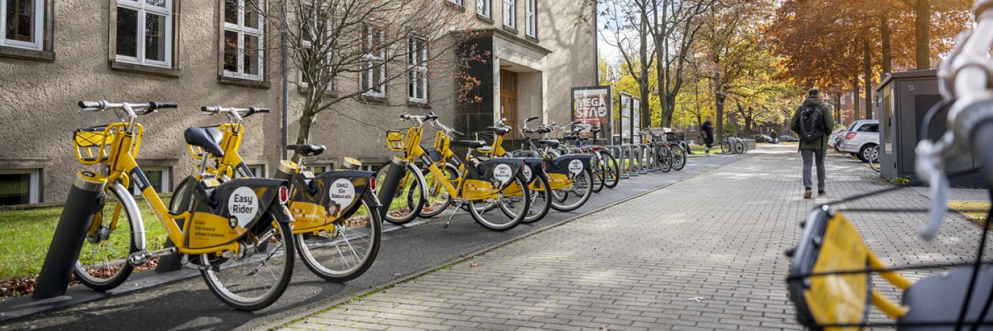 Außensicht auf ein TUD-Gebäude mit gelben Leihrädern davor.