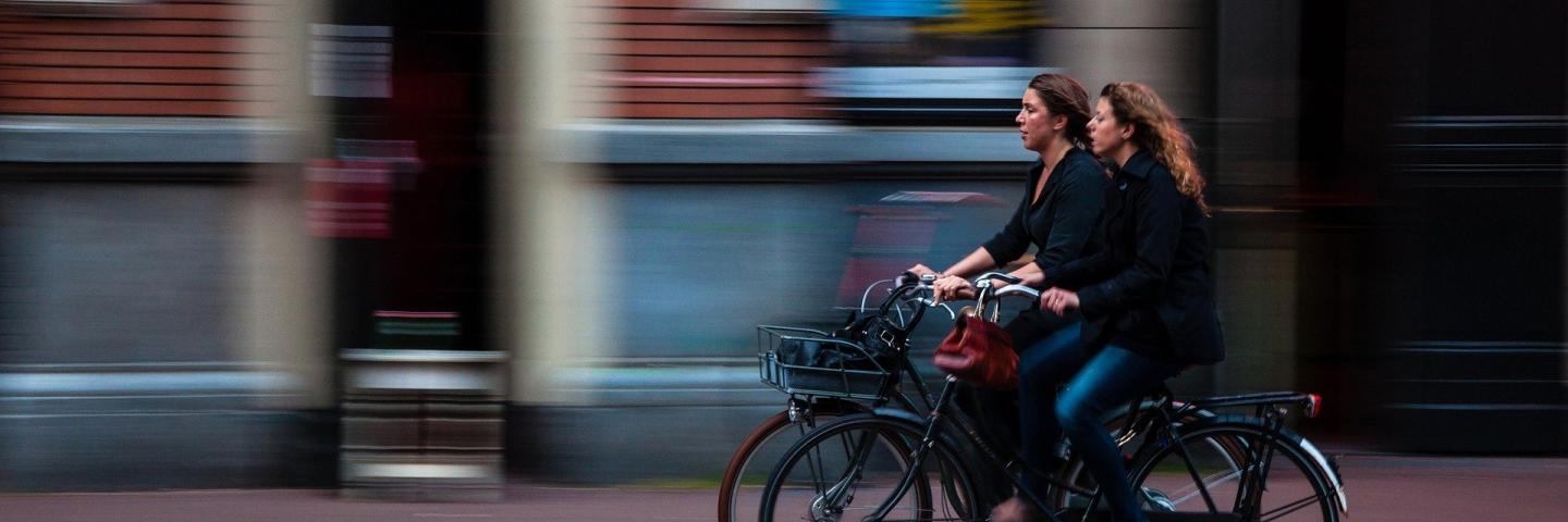 Zwei Frau auf Fahrrädern rollen durch die Stadt